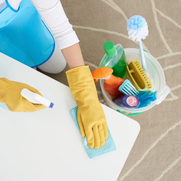 Woman cleaning table with detergent, view from above