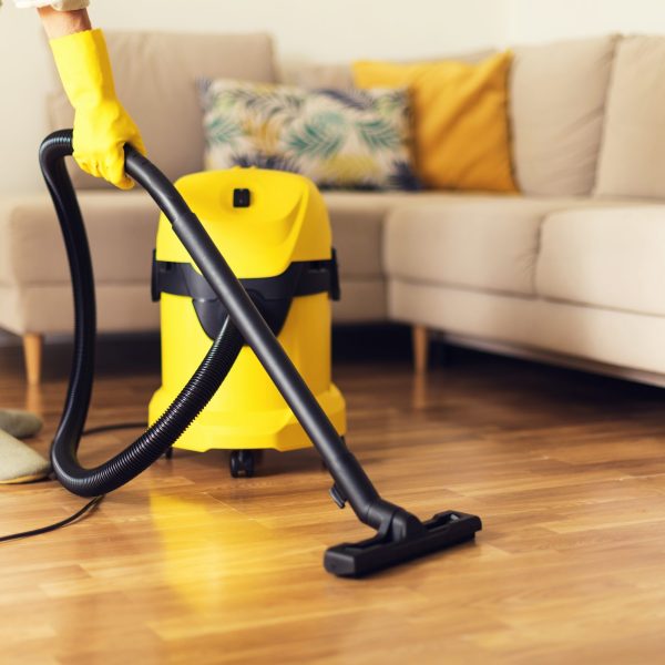 Woman cleaning sofa with yellow vacuum cleaner. Copy space. Cleaning service concept.